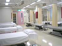 臨床実習室の画像です。病院風の広い部屋に処置用のブースがありベッドが配置されています。